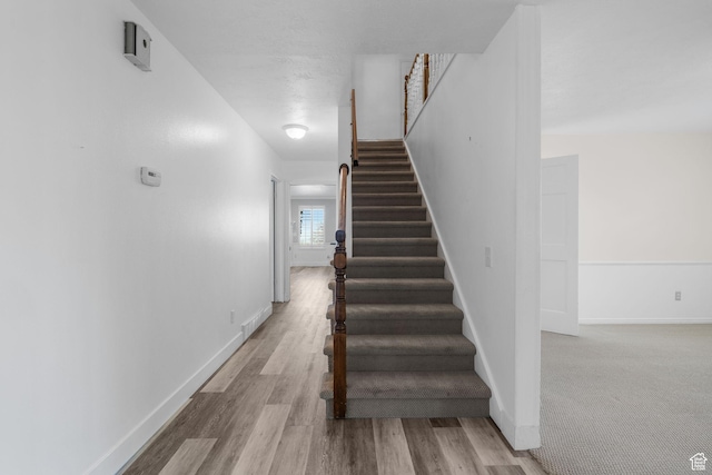 stairway with wood finished floors and baseboards