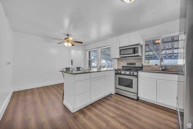 181 E 4300 S, Washington Terrace, UT 84405 - kitchen with dark stone countertops, a sink, a peninsula, appliances with stainless steel finishes, and dark wood-style floors