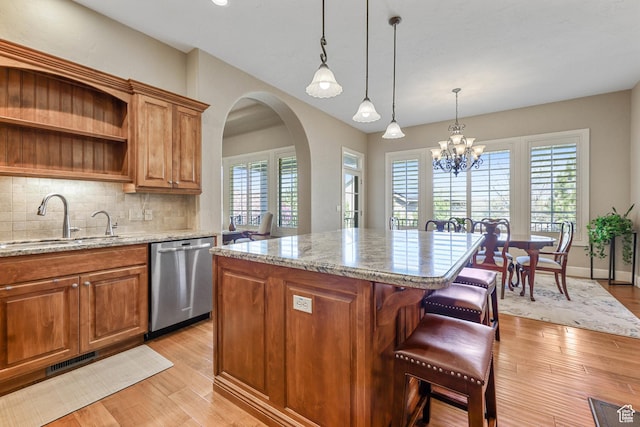 kitchen featuring brown cabinetry, stainless steel dishwasher, a sink, and visible vents