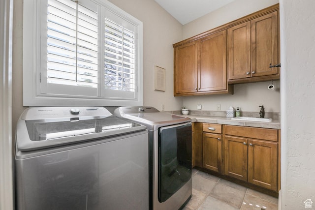 laundry area with washing machine and dryer, a sink, light tile patterned floors, and cabinet space