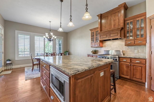 kitchen with brown cabinetry, appliances with stainless steel finishes, and an inviting chandelier