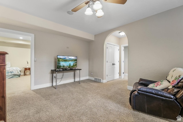 sitting room with ceiling fan, arched walkways, baseboards, carpet flooring, and visible vents