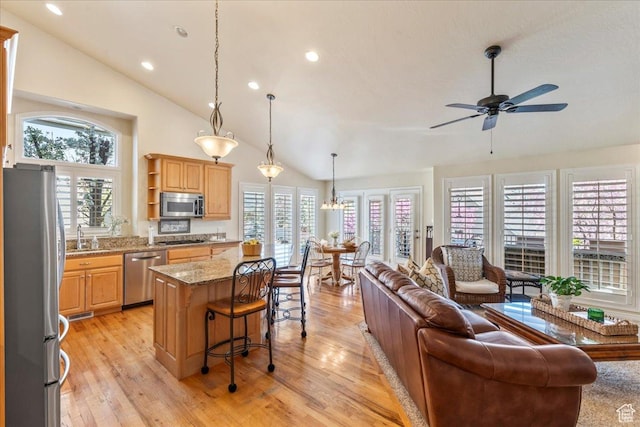 2010 E Rocklin Dr, Sandy, UT 84092 - kitchen featuring a kitchen island, light wood-style flooring, appliances with stainless steel finishes, open floor plan, and ceiling fan with notable chandelier