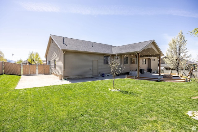 back of property with fence, a patio area, a lawn, and a gate