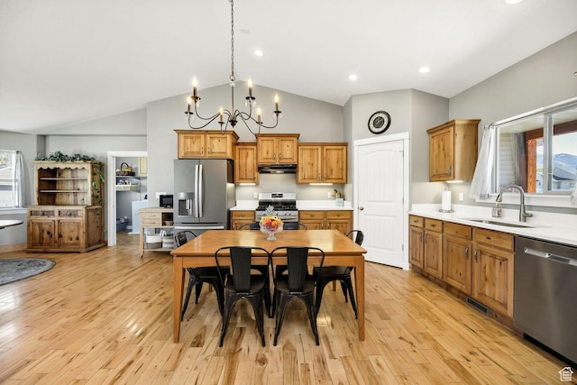 kitchen with stainless steel appliances, light countertops, under cabinet range hood, and a sink