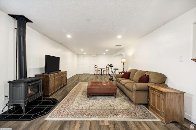 living area with baseboards, recessed lighting, a wood stove, and dark wood-style flooring