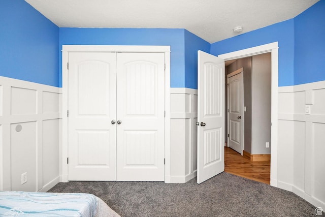 carpeted bedroom with wainscoting and a closet