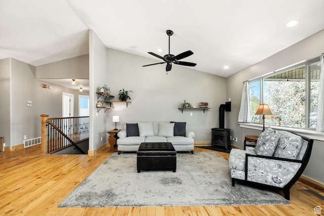 living area with wood-type flooring, a wood stove, and visible vents