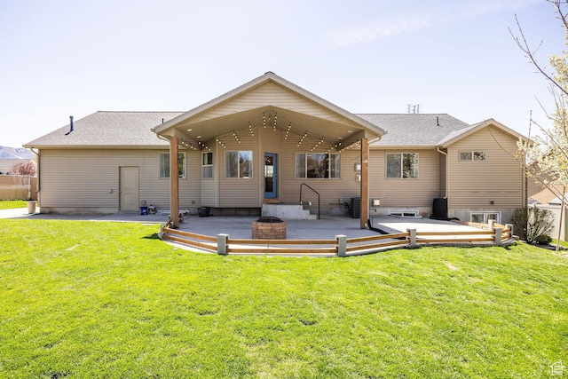 rear view of house with fence, a patio area, a lawn, and a shingled roof