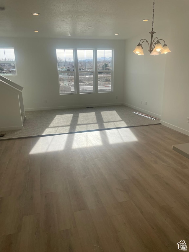 empty room featuring recessed lighting, baseboards, wood finished floors, and an inviting chandelier