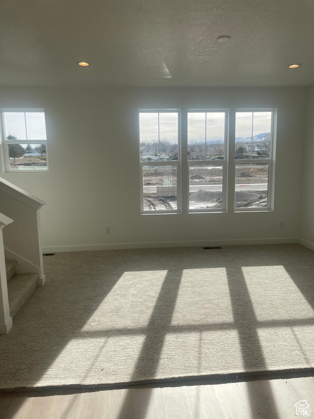 unfurnished room with baseboards, a healthy amount of sunlight, stairs, and visible vents