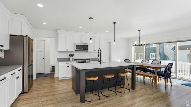 12373 S Pedroia St, Herriman, UT 84096 - kitchen featuring stainless steel appliances, light wood finished floors, a sink, a chandelier, and white cabinetry
