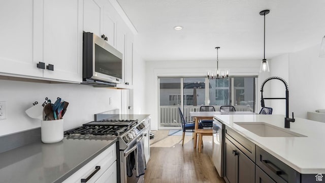 12373 S Pedroia St, Herriman, UT 84096 - kitchen with stainless steel appliances, a sink, light wood-style floors, a chandelier, and white cabinetry