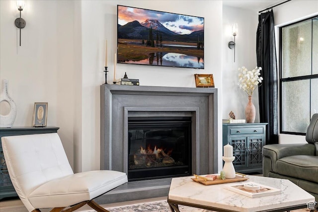 sitting room featuring a glass covered fireplace and wood finished floors