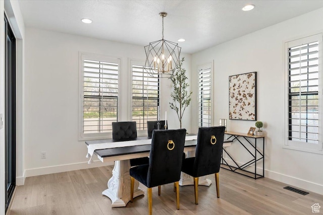 dining space featuring baseboards, a notable chandelier, visible vents, and light wood-style flooring