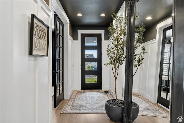 foyer entrance featuring wood finished floors, recessed lighting, a textured ceiling, and a decorative wall