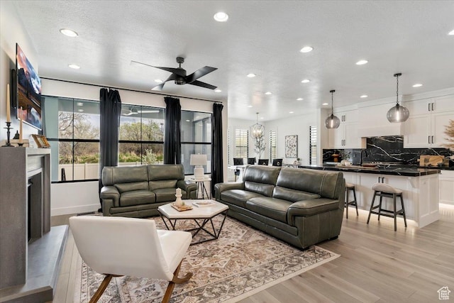 living area with light wood finished floors, recessed lighting, a textured ceiling, and ceiling fan