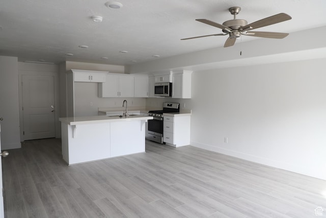 kitchen with appliances with stainless steel finishes, light countertops, white cabinets, ceiling fan, and baseboards