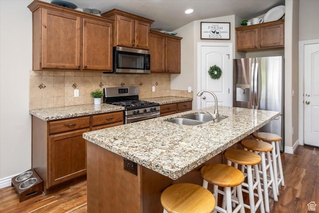 4206 Rose Springs Rd, Erda, UT 84074 - kitchen featuring appliances with stainless steel finishes, a sink, dark wood-type flooring, brown cabinetry, and decorative backsplash