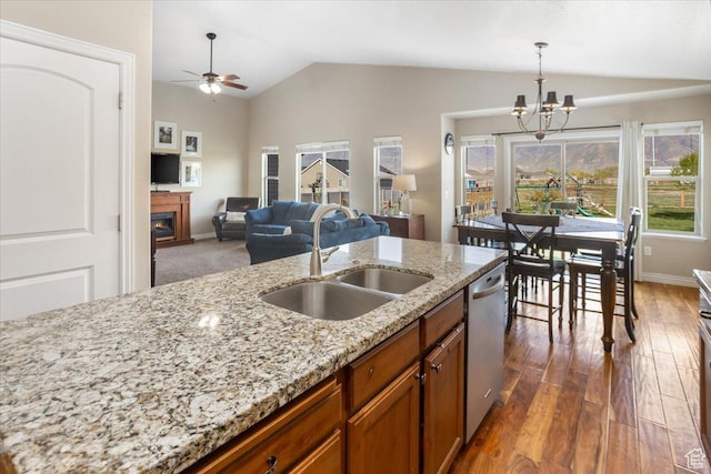 4206 Rose Springs Rd, Erda, UT 84074 - kitchen featuring a sink, vaulted ceiling, brown cabinetry, a chandelier, and a lit fireplace