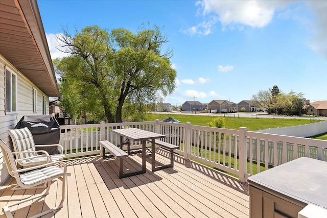 wooden deck featuring a yard, a residential view, and a grill