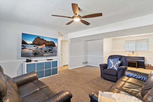 living room featuring light carpet, visible vents, a textured ceiling, and ceiling fan