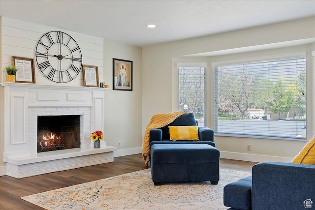 sitting room with baseboards, a brick fireplace, wood finished floors, and recessed lighting