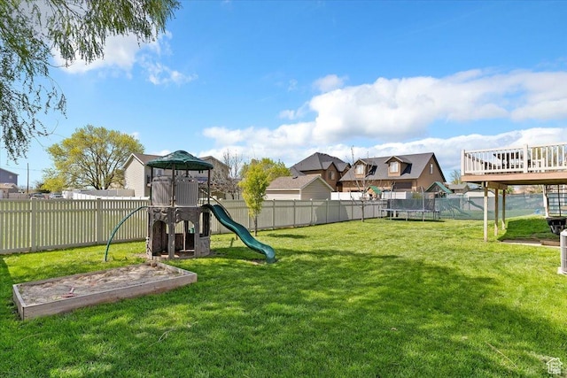 view of yard featuring a trampoline, a fenced backyard, and a playground