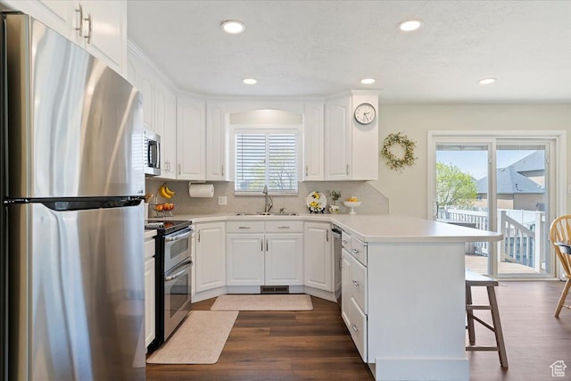 kitchen with recessed lighting, a kitchen breakfast bar, stainless steel appliances, a sink, and a peninsula