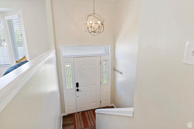 foyer featuring wood finished floors, baseboards, and a notable chandelier