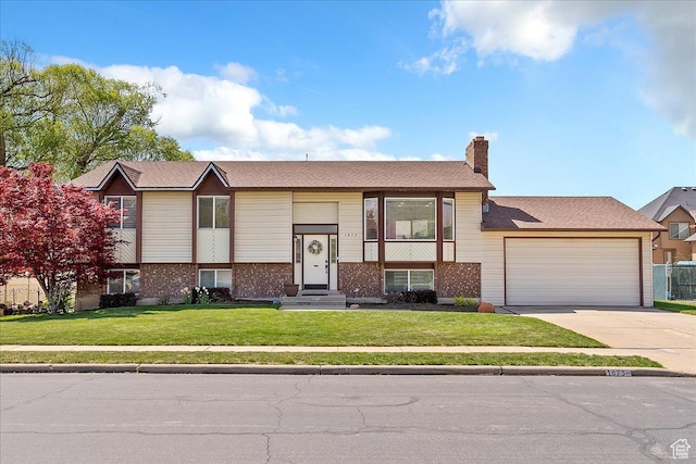 raised ranch featuring an attached garage, brick siding, a front yard, and concrete driveway