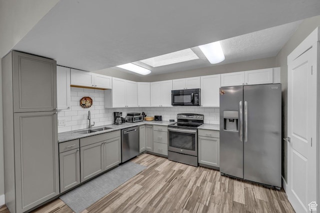 kitchen featuring light countertops, gray cabinetry, a sink, and appliances with stainless steel finishes