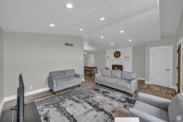 living room featuring baseboards, wood finished floors, visible vents, and a textured ceiling