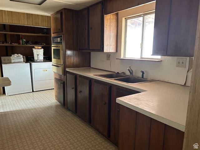 kitchen featuring light countertops, stainless steel oven, separate washer and dryer, and a sink