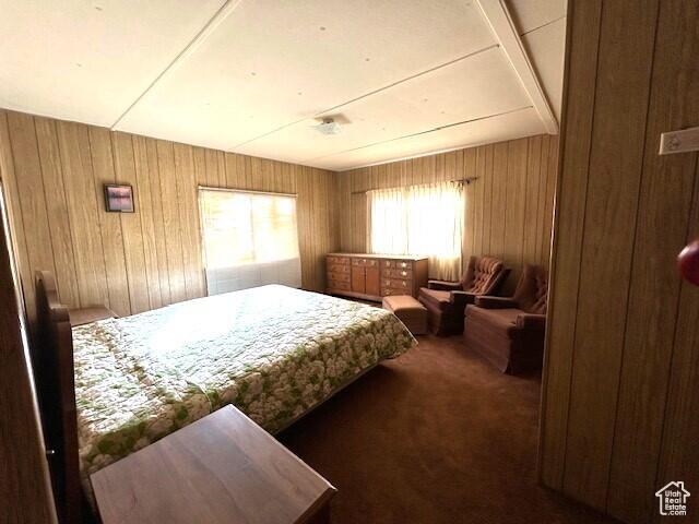 carpeted bedroom with multiple windows and wooden walls