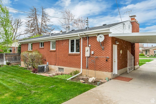 2344 E Arnett Dr, Millcreek, UT 84109 - view of home's exterior featuring central AC, a lawn, a chimney, fence, and brick siding
