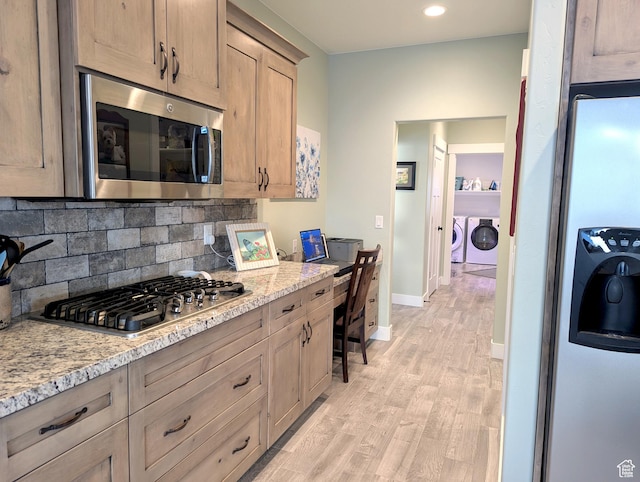 627 W Olympic Ln, Elk Ridge, UT 84651 - kitchen with washer and clothes dryer, light wood-type flooring, decorative backsplash, light stone counters, and appliances with stainless steel finishes