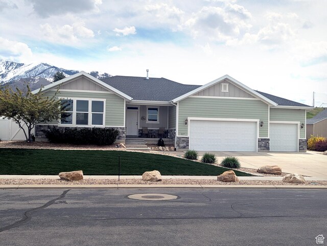 view of front of house featuring a front lawn, board and batten siding, driveway, stone siding, and a garage