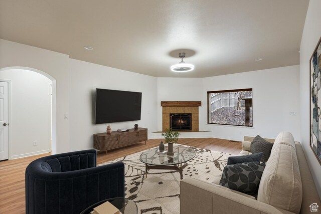 9226 N Mount Airey Dr W, Eagle Mountain, UT 84005 - living area with light wood-style flooring, arched walkways, a tiled fireplace, and baseboards