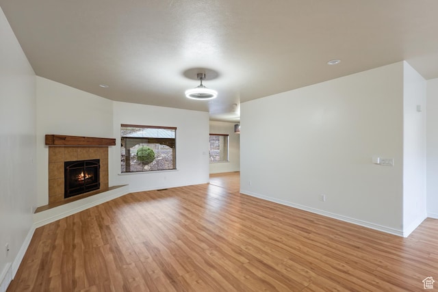 9226 N Mount Airey Dr W, Eagle Mountain, UT 84005 - unfurnished living room with light wood finished floors, baseboards, and a tiled fireplace