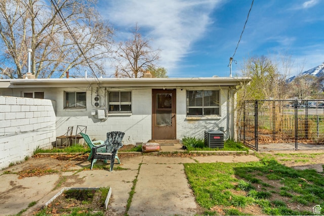 view of front of home featuring central AC, a gate, fence, and concrete block siding
