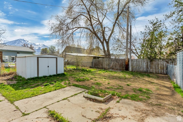view of yard with an outdoor structure, fence, a storage shed, and a mountain view
