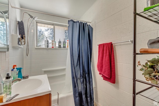 bathroom featuring a wealth of natural light, vanity, shower / tub combo with curtain, and concrete block wall