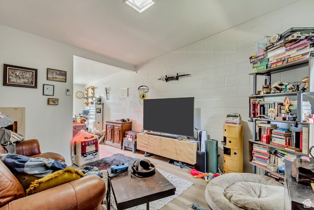 living area with concrete block wall, wood finished floors, and vaulted ceiling
