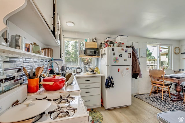 kitchen with a healthy amount of sunlight, light wood-style floors, white appliances, and light countertops