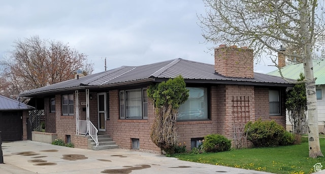 273 S 7th St S, Montpelier, ID 83254 - view of front of house with concrete driveway, an outdoor structure, a chimney, a metal roof, and brick siding