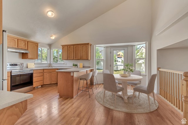 6706 S Adventure Way, West Jordan, UT 84084 - kitchen with stainless steel electric stove, high vaulted ceiling, under cabinet range hood, a sink, and a kitchen breakfast bar