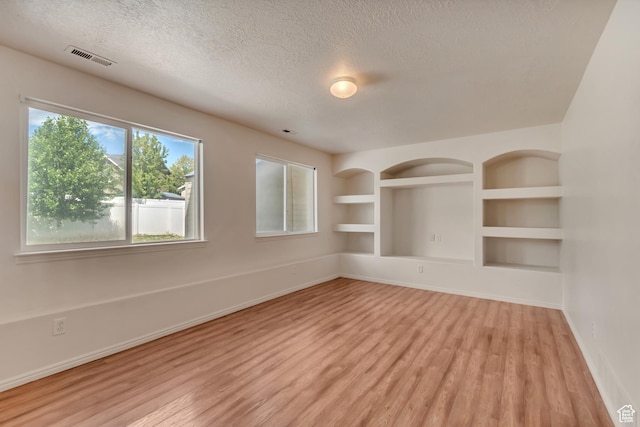 6706 S Adventure Way, West Jordan, UT 84084 - unfurnished room featuring a textured ceiling, visible vents, built in shelves, light wood-style flooring, and baseboards