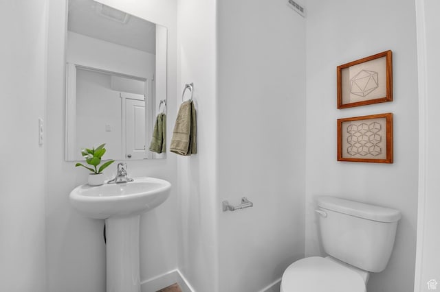 bathroom featuring visible vents, toilet, baseboards, and a sink