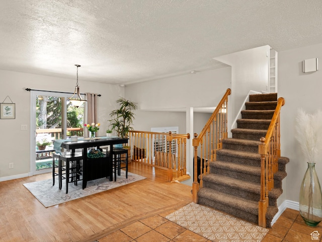 dining space with wood finished floors, a textured ceiling, and baseboards
